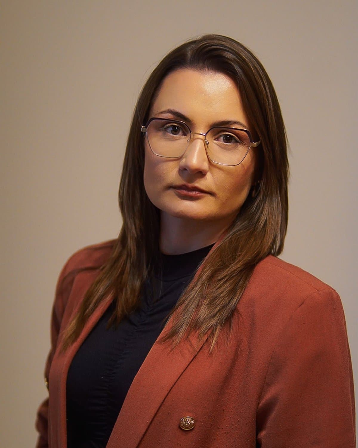 Retrato de Jane Comunello, de óculos e blazer cor de tijolo